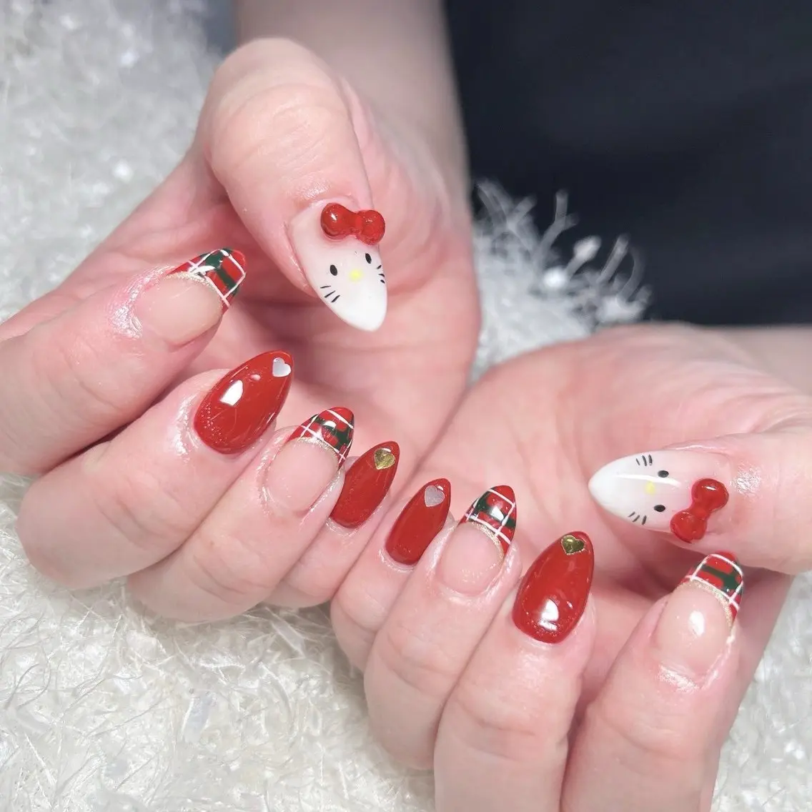Short almond nails in red and white with green tartan plaid tips, Hello Kitty faces with 3D red bows and gold heart studs