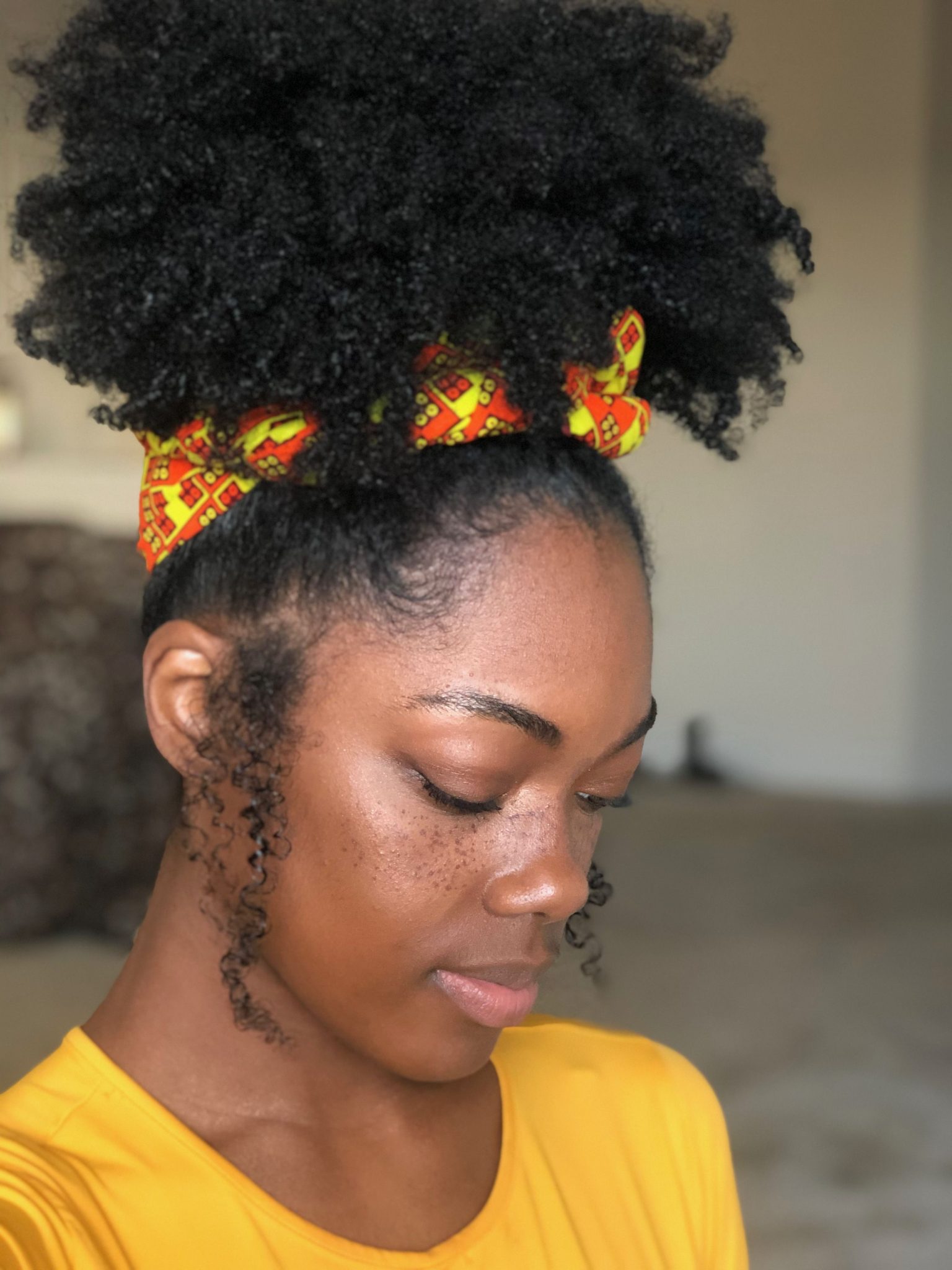 Woman with a natural high puff wearing a colorful African-print headband