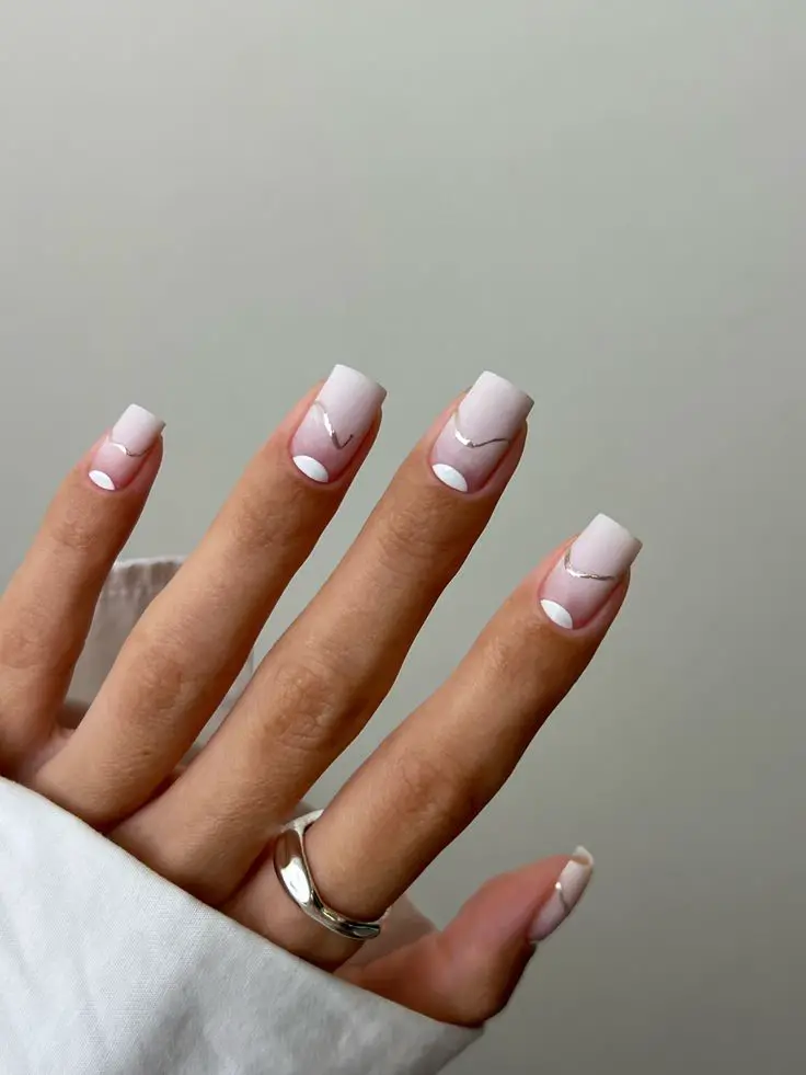 Short square nails with a soft white French tip and silver swirl accents