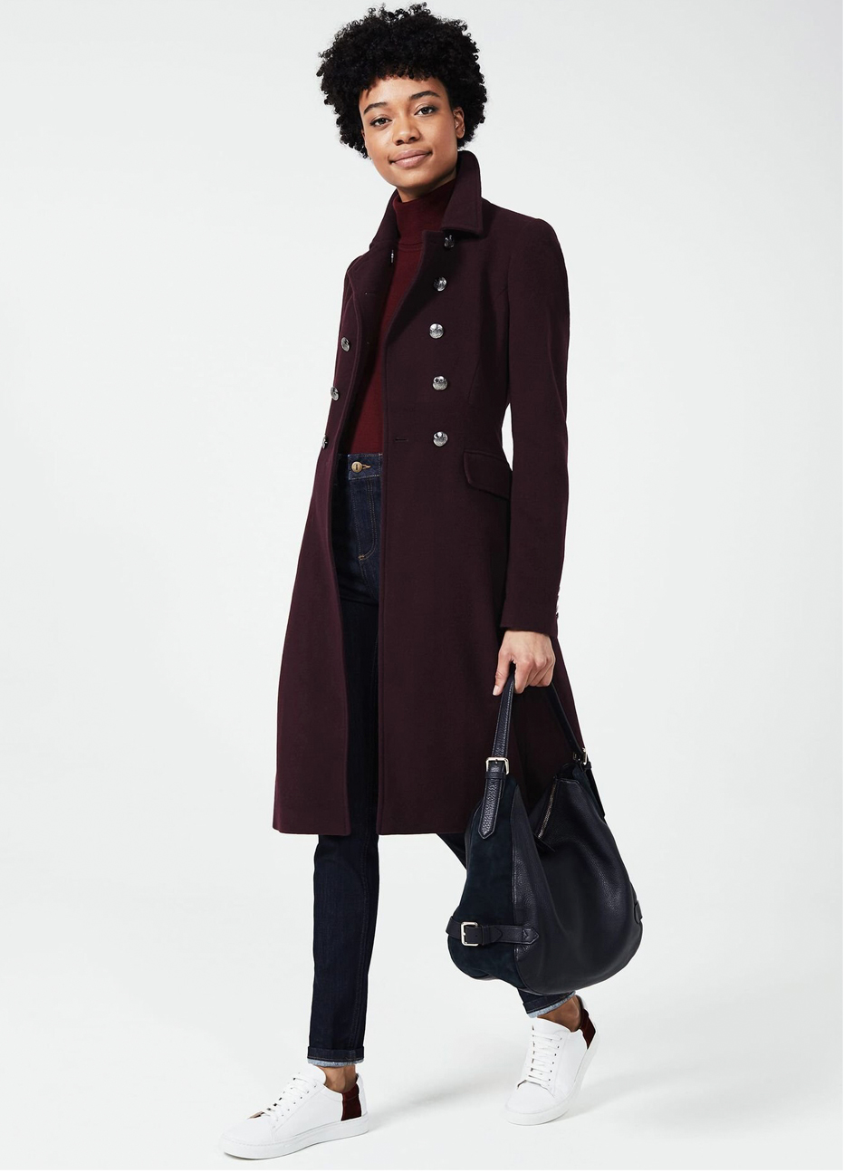 Woman in a burgundy double-breasted coat with a burgundy turtleneck and dark jeans