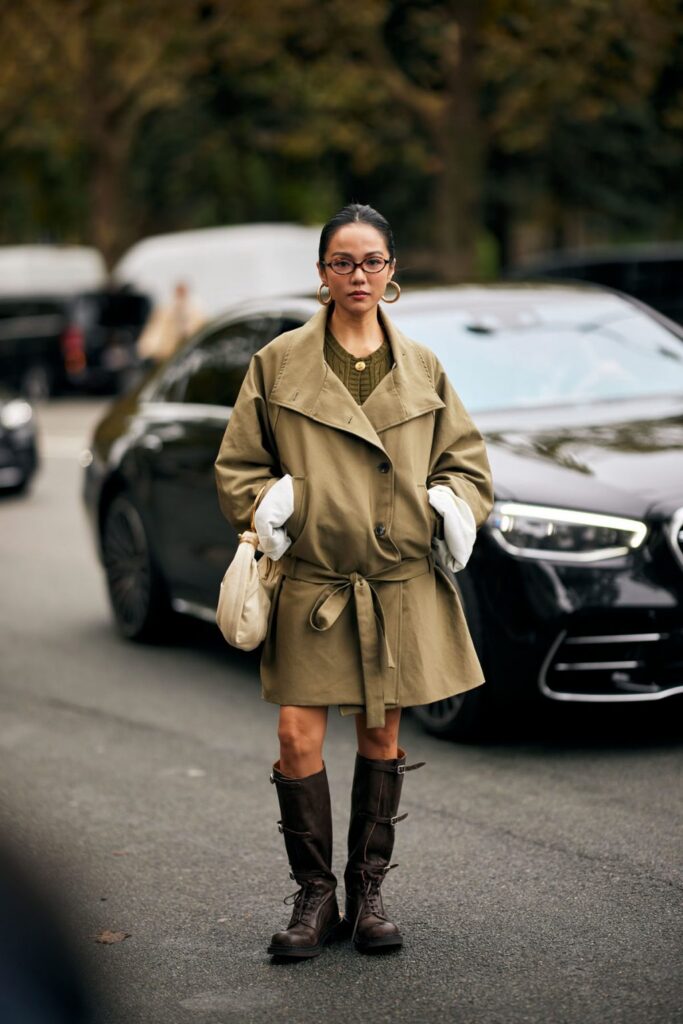 Woman in a belted khaki trench-coat dress and knee-high brown lace-up combat boots