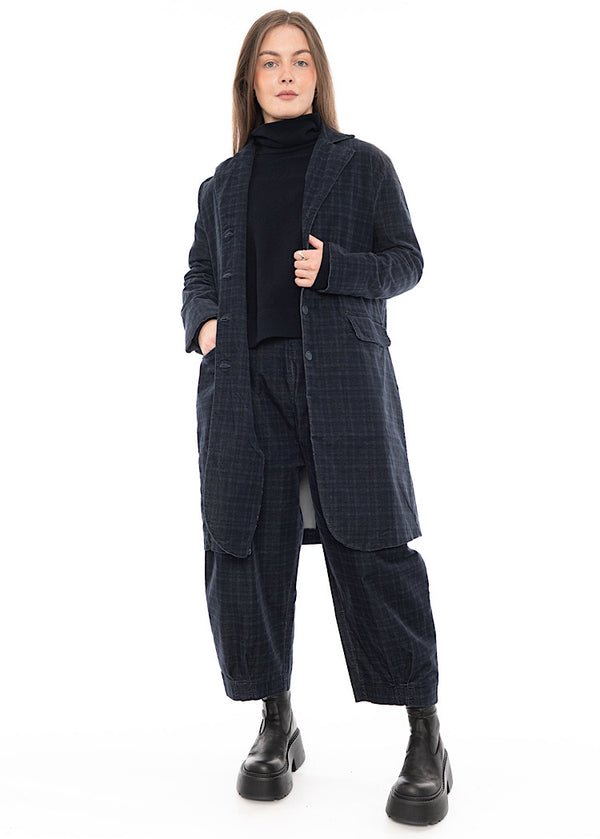 Woman wearing a dark plaid co-ord with a longline jacket and cropped pants, black turtleneck and black platform ankle boots