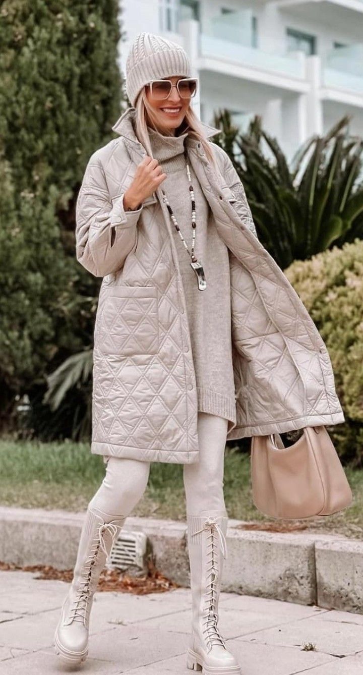 Woman in a long beige quilted coat over a beige knit co-ord set with lace-up boots