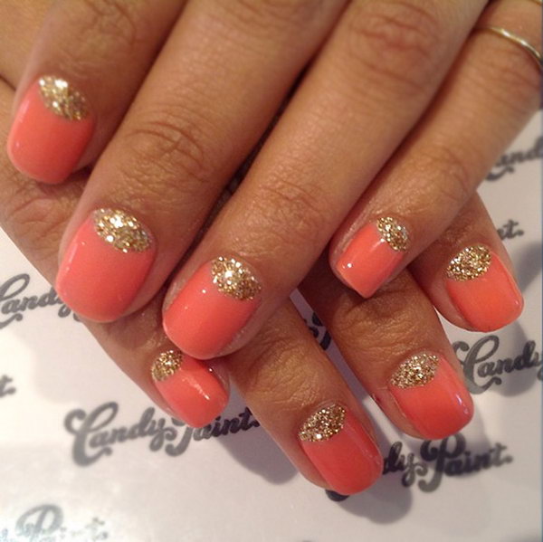 Coral nails with gold glitter half-moon accents at the cuticle