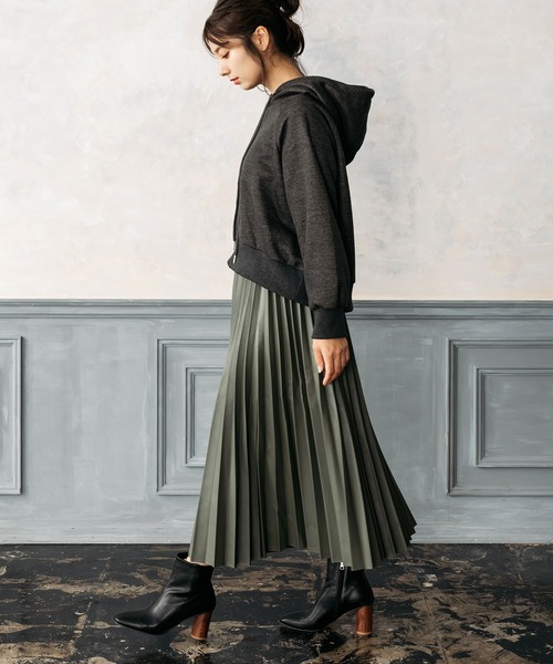 Woman in charcoal zip-up hoodie, olive pleated midi skirt and black heeled ankle boots