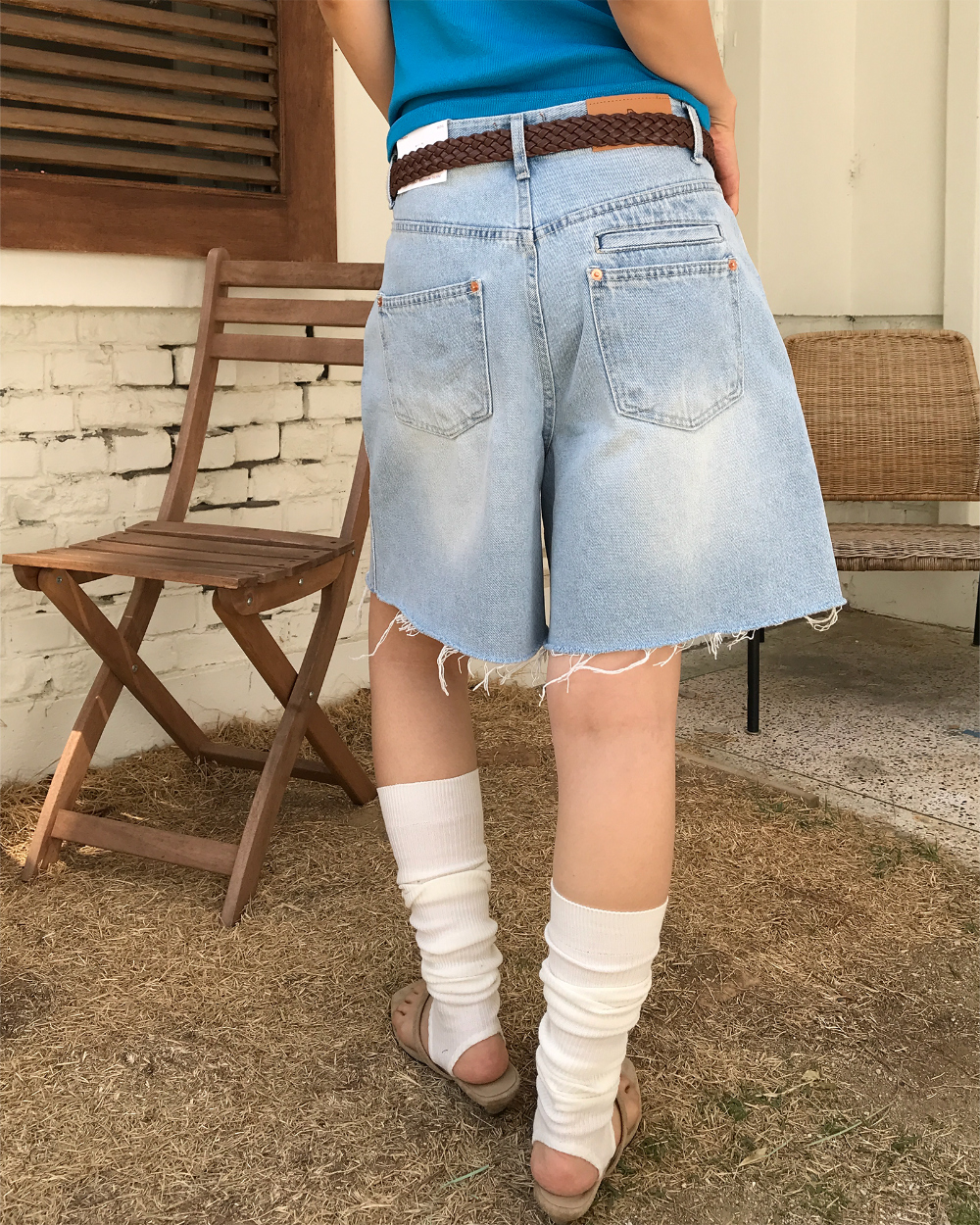 White ribbed leg warmers with light wash denim shorts, a turquoise tee and neutral slides, back view
