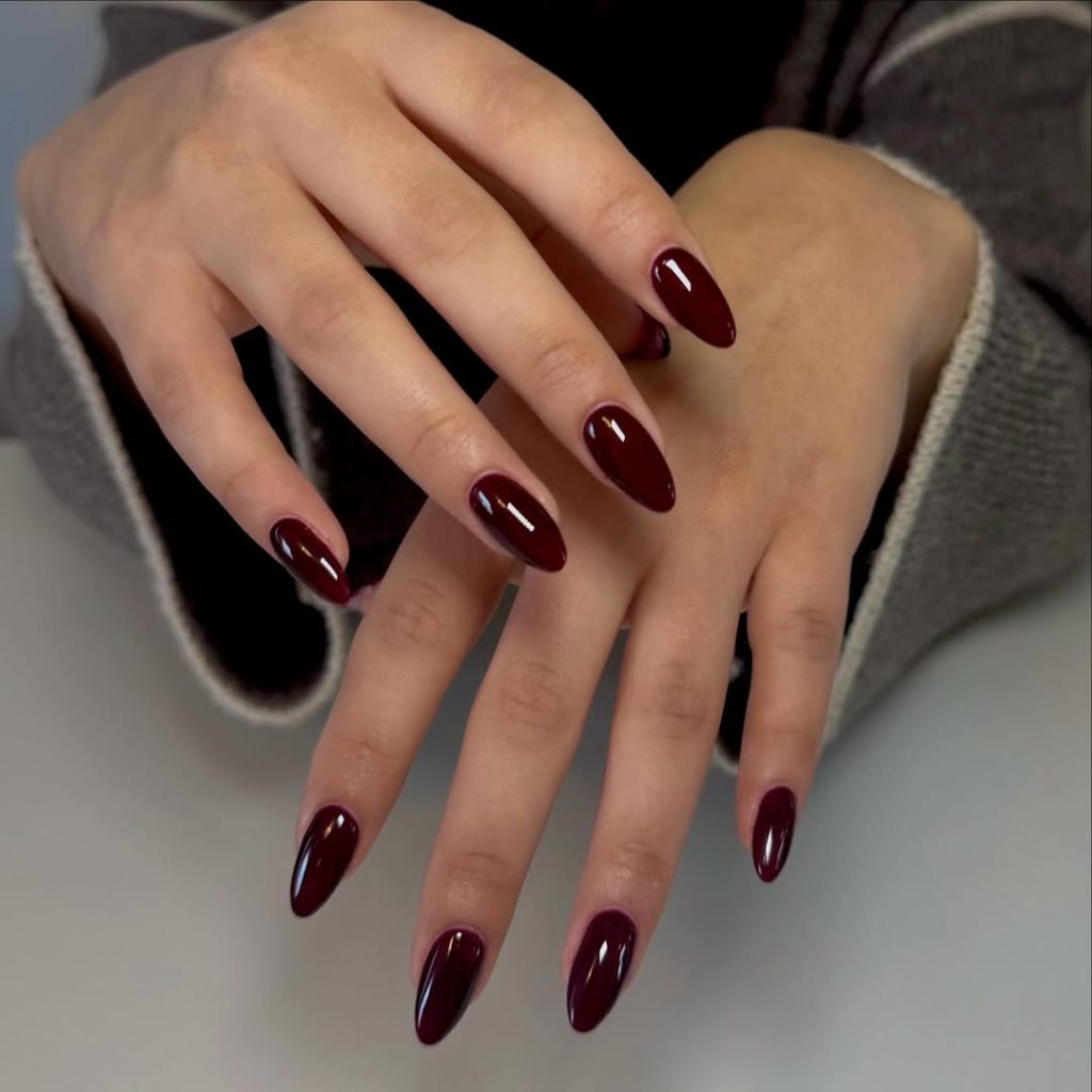 Glossy dark cherry red polish on almond-shaped nails
