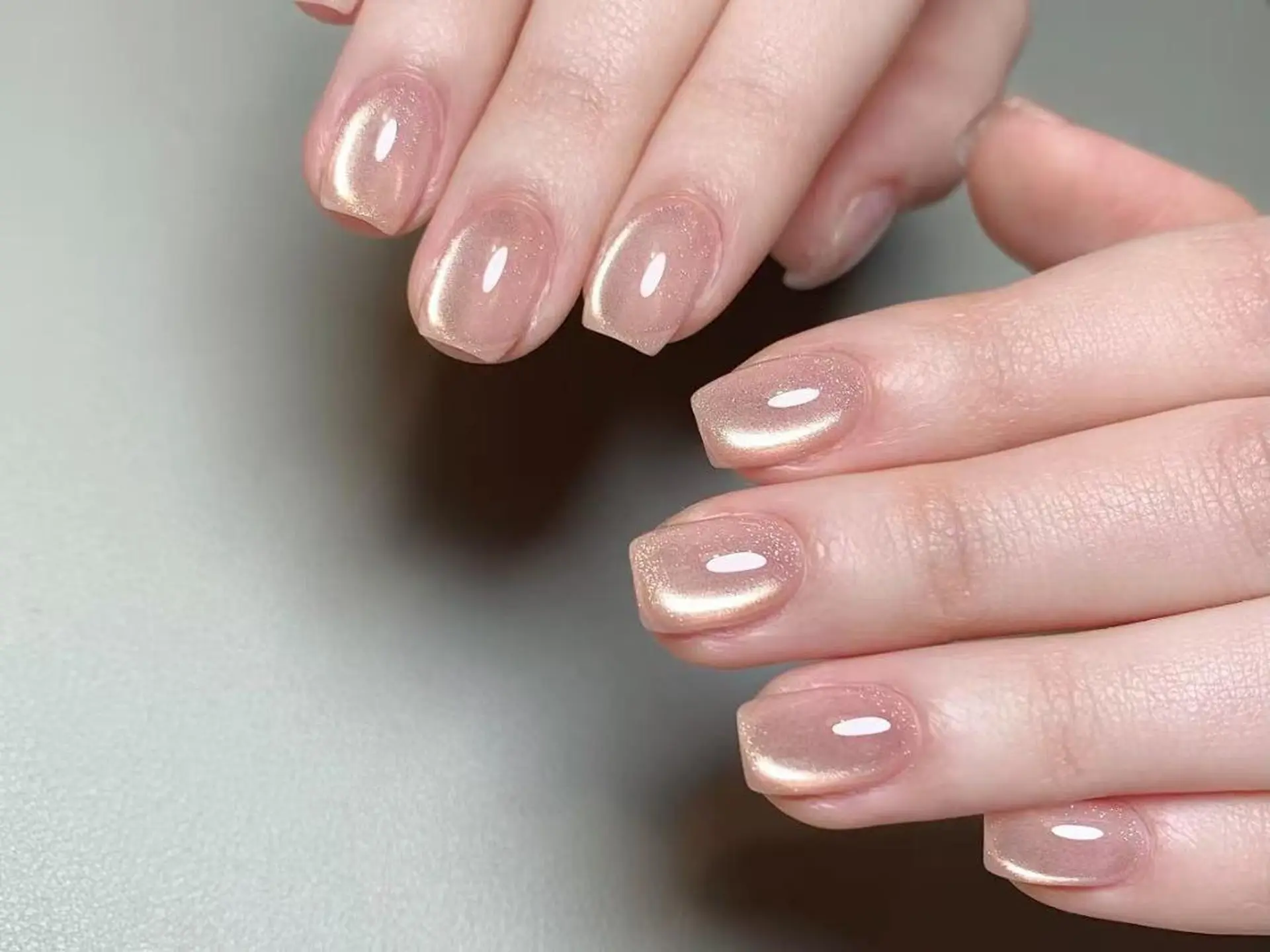 Short square nails in sheer nude with a champagne-gold magnetic cat-eye shimmer.