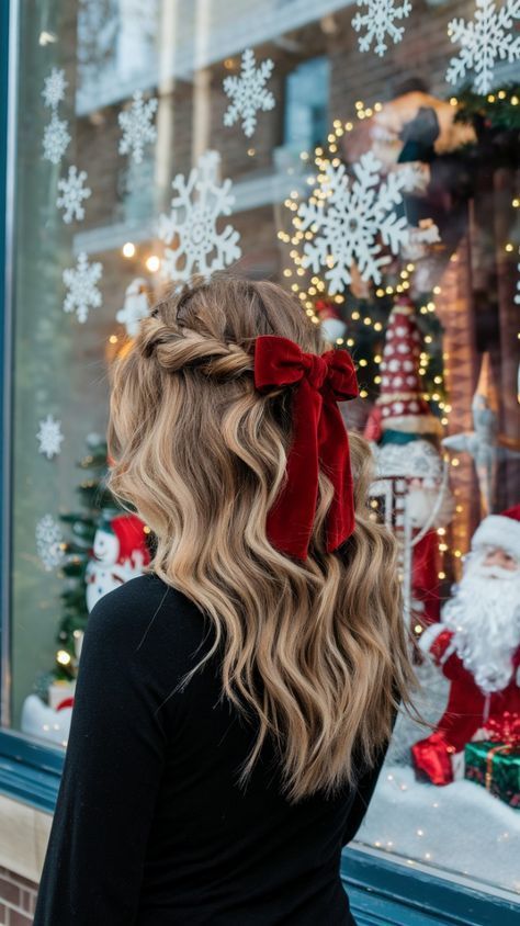 Half-up hairstyle with loose curls, a braided crown and a deep red velvet ribbon bow