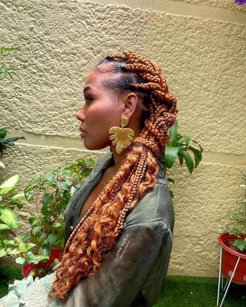 Copper ginger braids with golden undertones on a Black woman outdoors