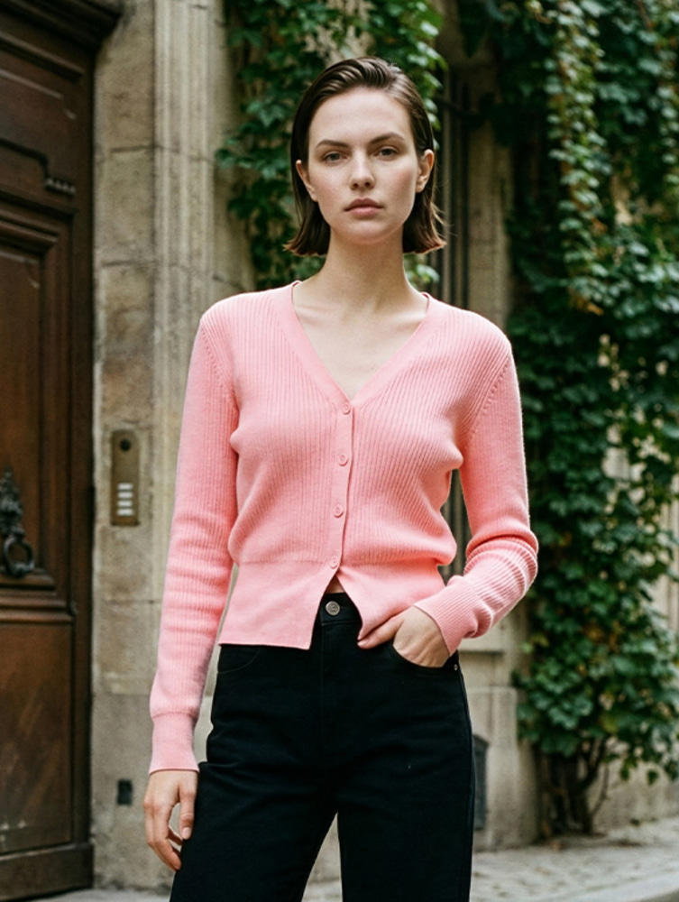 Woman wearing a pink V-neck cardigan fully buttoned as a top with black skinny jeans, outdoors