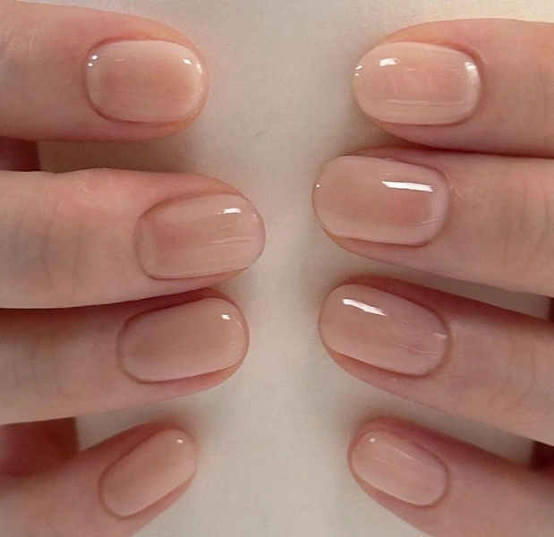 Soft nude beige nail polish with subtle sheen on short natural nails