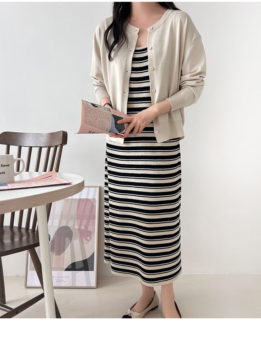 Woman wearing a cream cardigan open over a black and white striped knit midi dress with nude bow flats