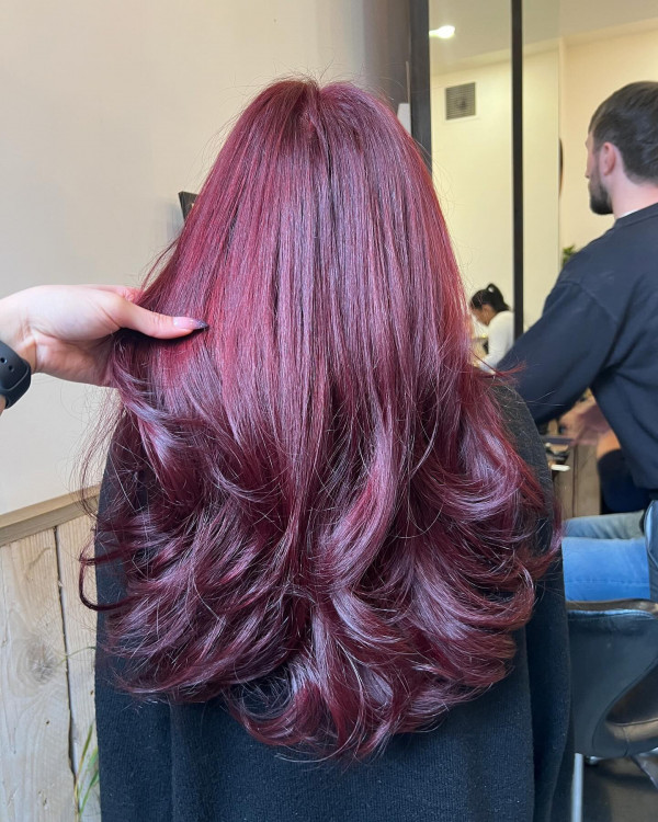 Back view of a bouncy cherry cola salon blowout with magenta glow