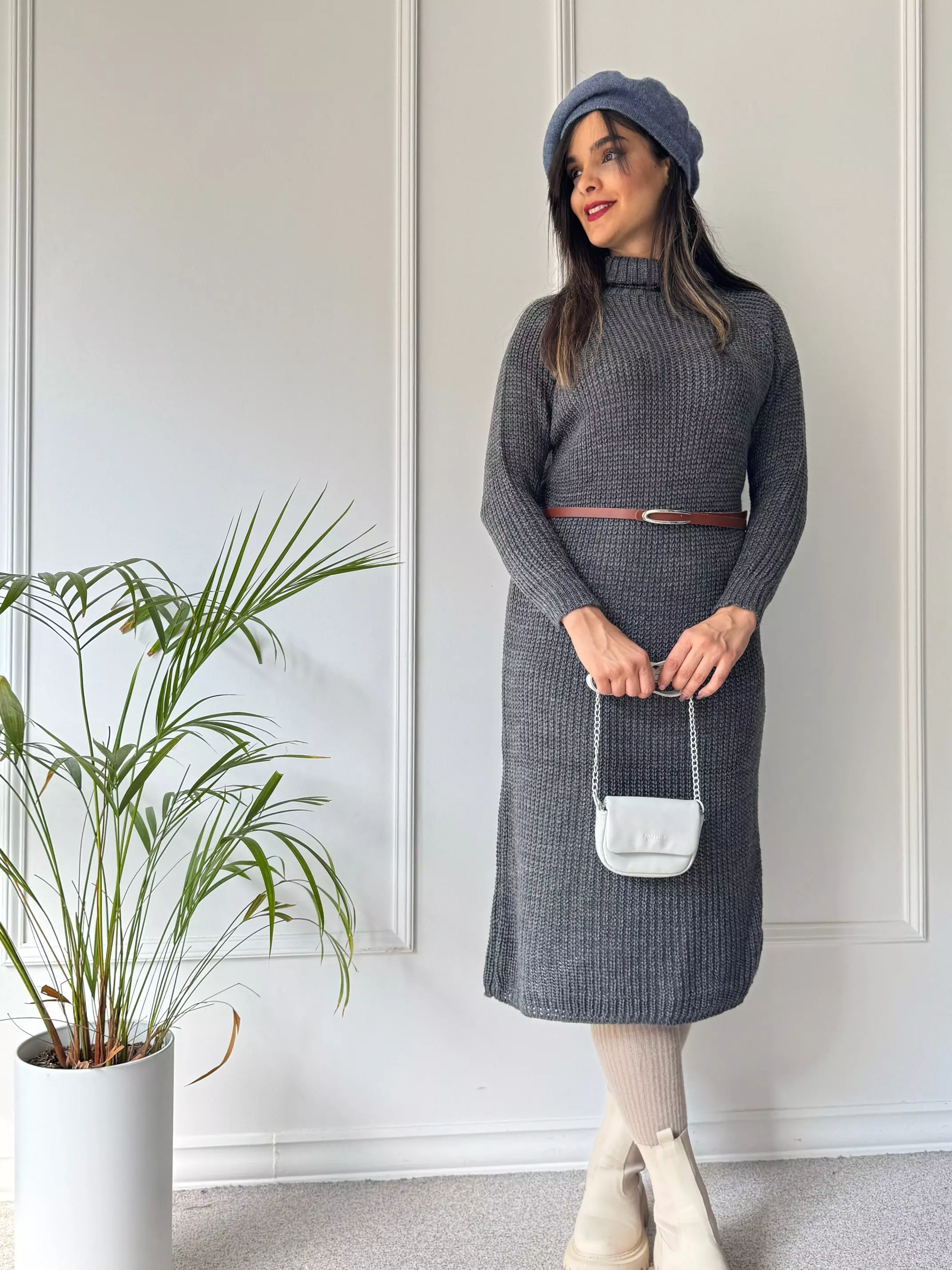 Woman in a belted charcoal knit midi dress with cream boots and a grey beret