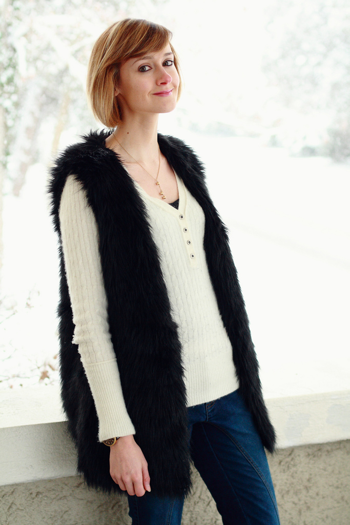 Woman wearing a faux fur vest over a sweater with wide-leg trousers