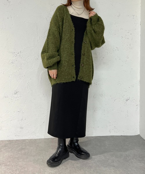 Woman in a green fuzzy oversized cardigan with a black slip dress and chunky black boots