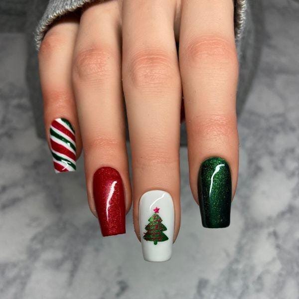 Glitter Christmas tree nail art on white with red and green glitter nails and a striped accent