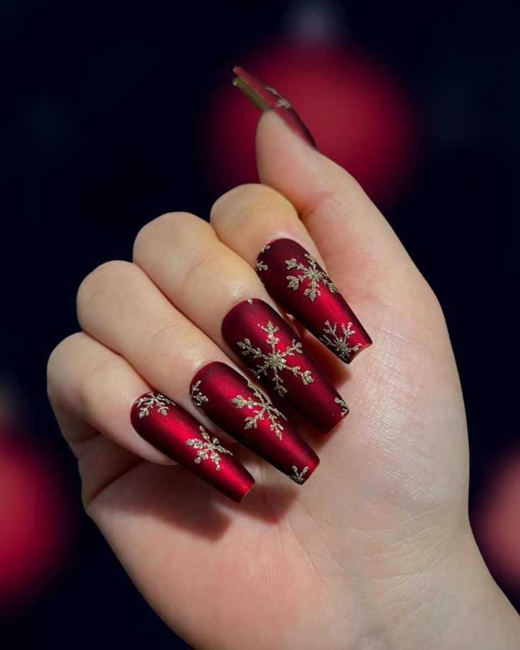 Deep red coffin acrylic nails with gold filigree-style snowflake and ornament nail art