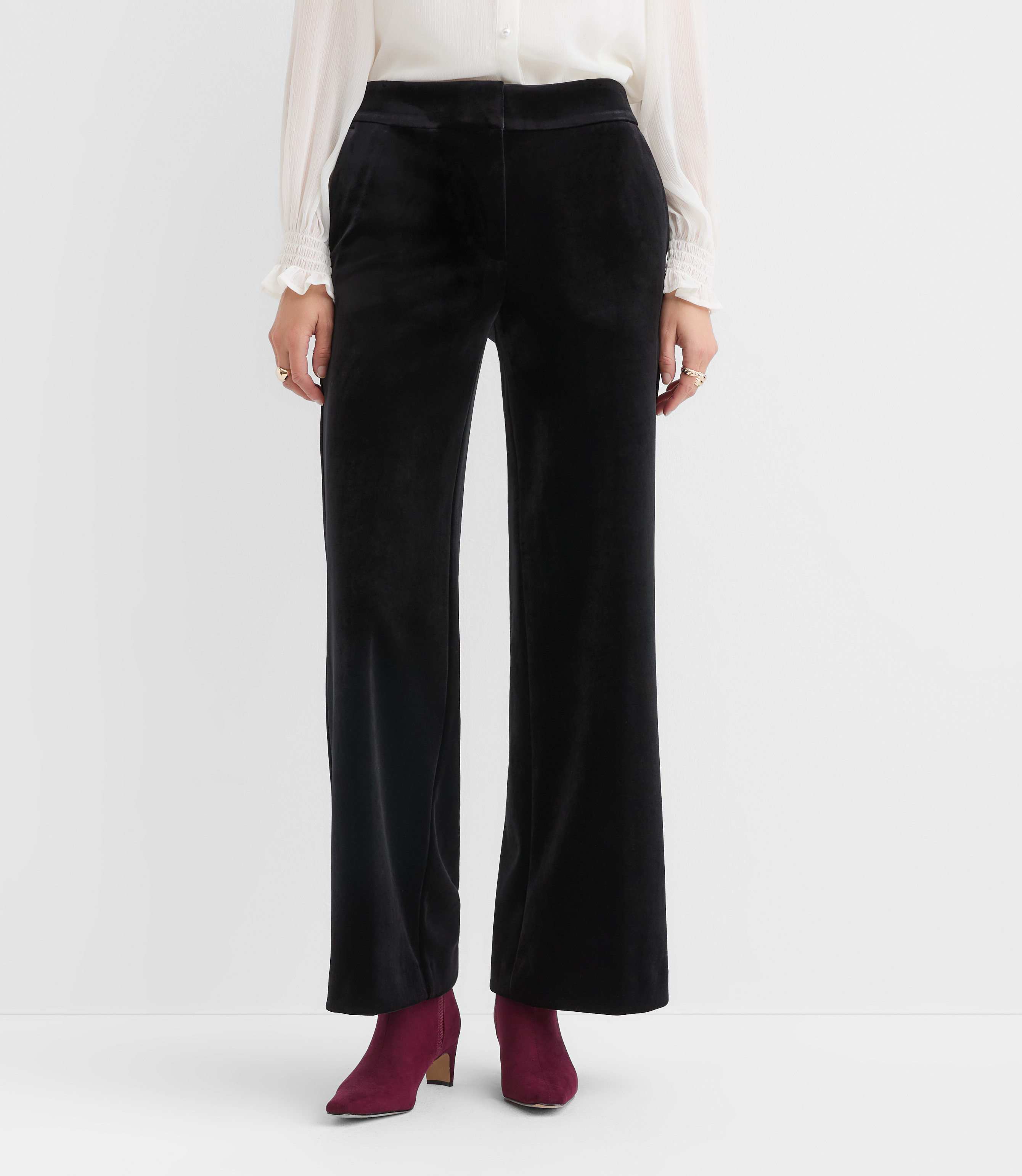 Woman in wine suede ankle boots with black velvet wide-leg trousers and a white blouse
