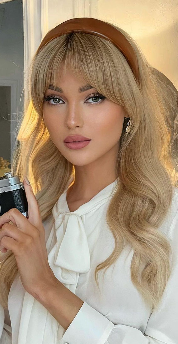 Blonde woman with curtain bangs wearing a brown padded leather headband