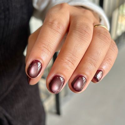 Short rounded nails in deep plum with a magnetic cat-eye shimmer band