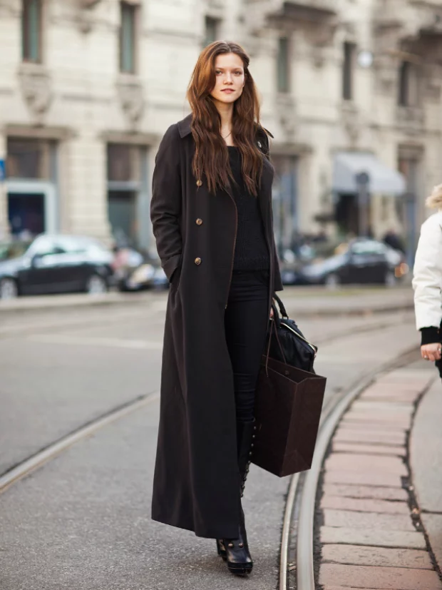 Woman in a black car coat with boots in a winter street-style look