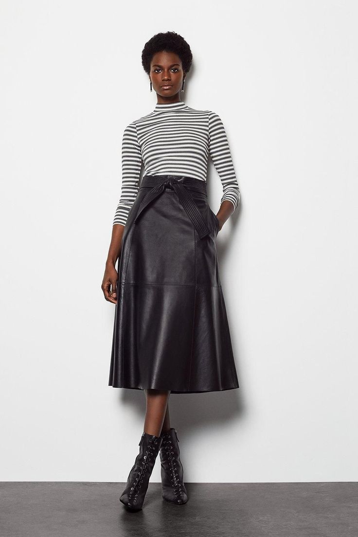 Woman in black turtleneck, leather midi skirt and boots, winter outfit