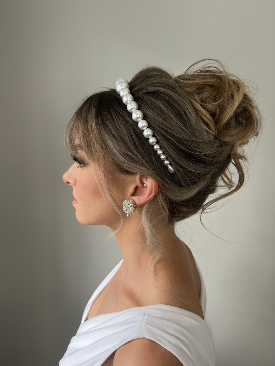 Woman with a messy topknot wearing a pearl-embellished headband