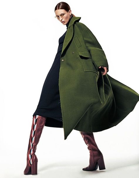 Woman wearing a forest green coat with brown boots in a winter outfit