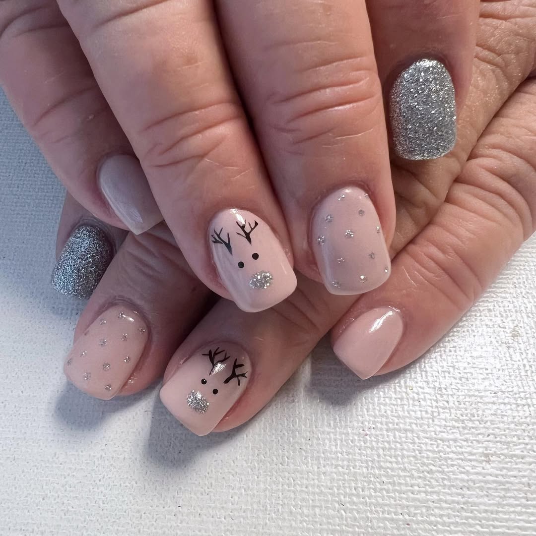 Short nude pink Christmas nails with reindeer faces and silver glitter