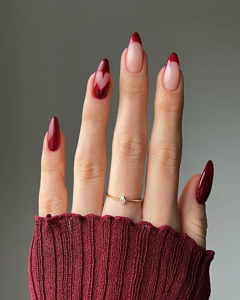 Almond nails in deep burgundy with burgundy French tip accents and heart detail