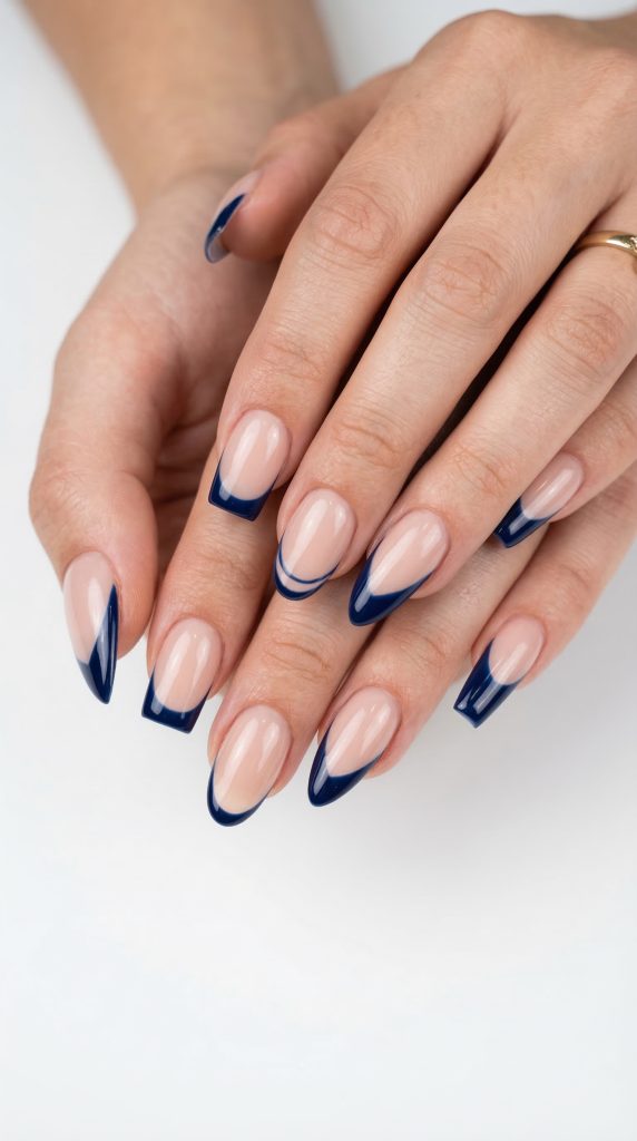 Nails with a nude base and dark midnight blue French tips