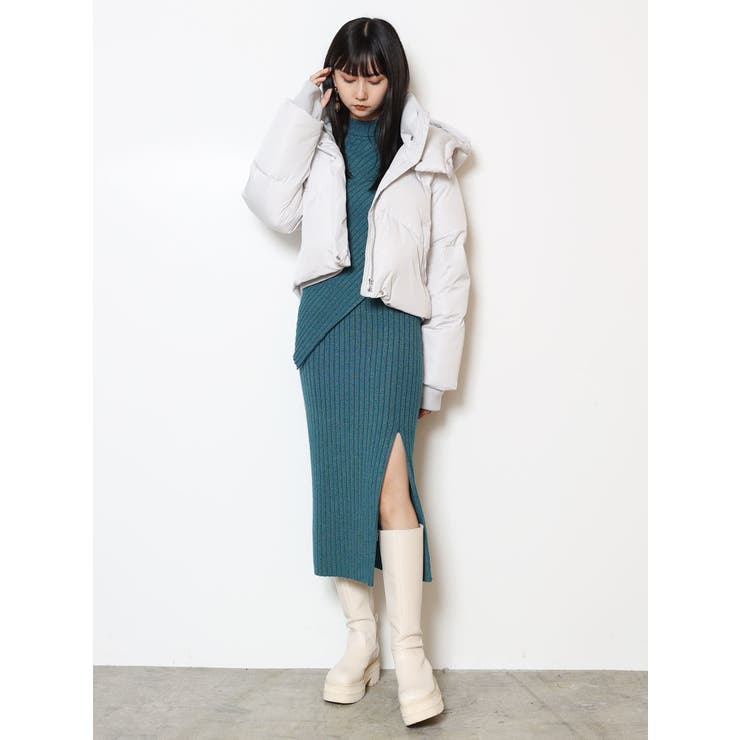 Woman in a white cropped puffer jacket over a teal ribbed knit midi dress with a side slit and white knee-high boots