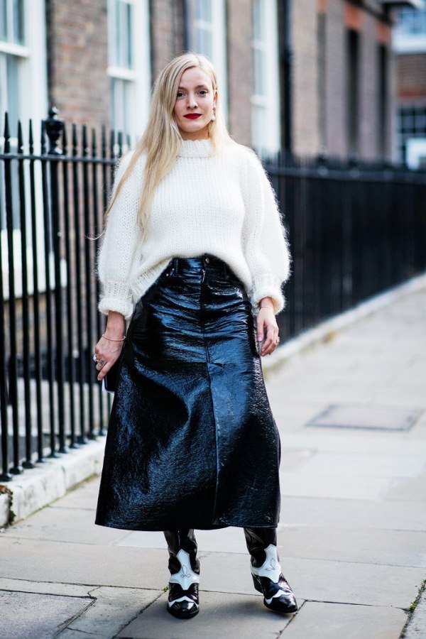 Woman in a white chunky sweater with a black patent midi skirt and two-tone cowboy boots on a London street