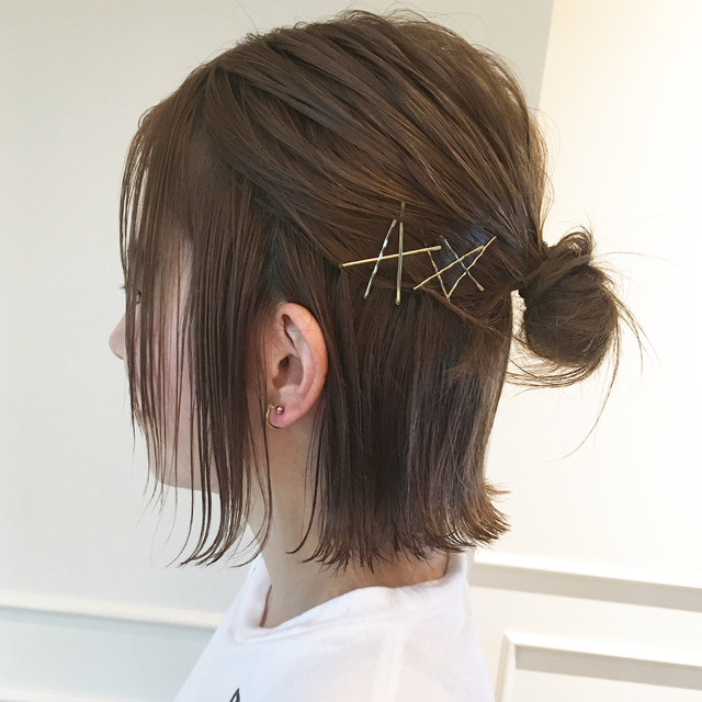 Side profile of a half-up mini bun secured with gold hair pins