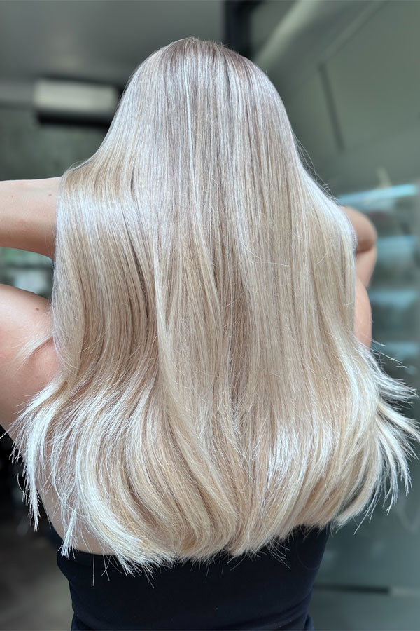 Back view of a voluminous frosty blonde ombre blowout with shadowed roots