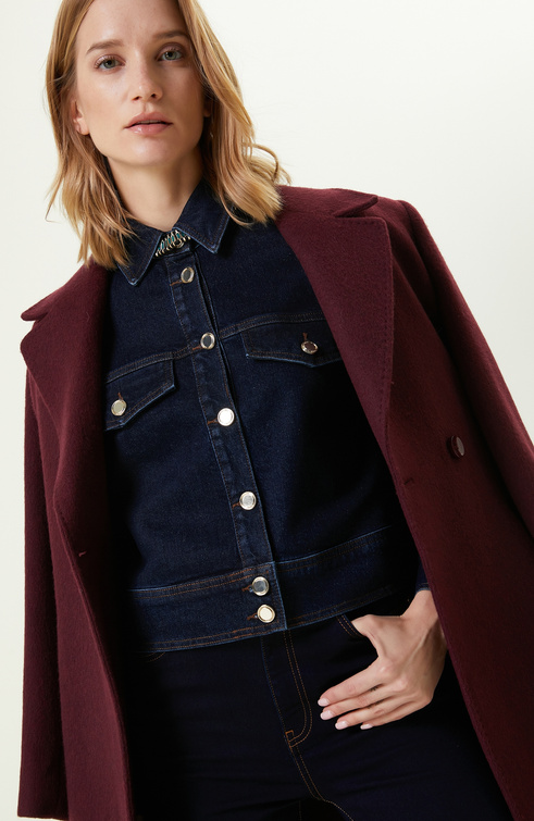 Burgundy wool coat worn over a dark denim shirt with dark jeans