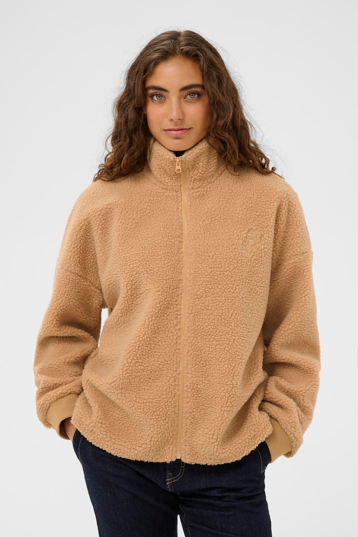 Woman in a camel teddy fleece jacket with dark jeans