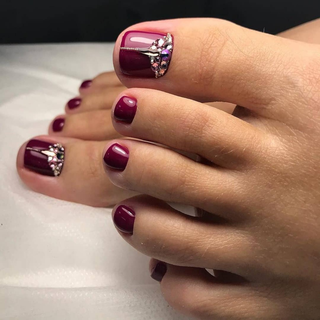 Burgundy pedicure with a rhinestone cluster on the big toes