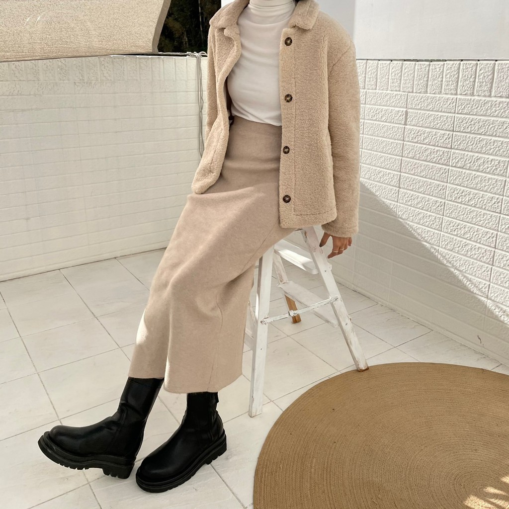 Woman in a teddy fleece jacket, white turtleneck, beige knit midi skirt and black Chelsea boots