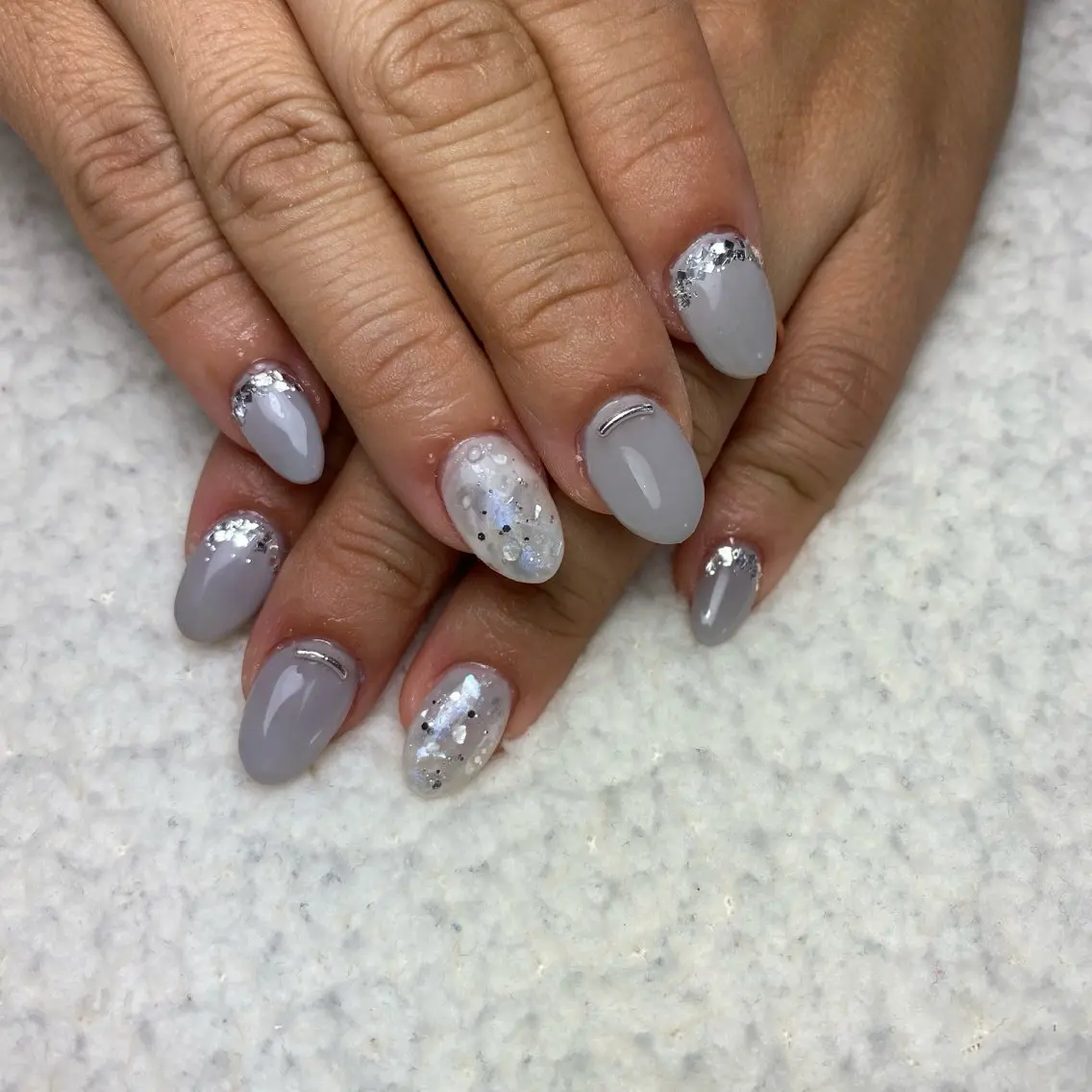 Short almond nails in cool grey with iridescent flakes