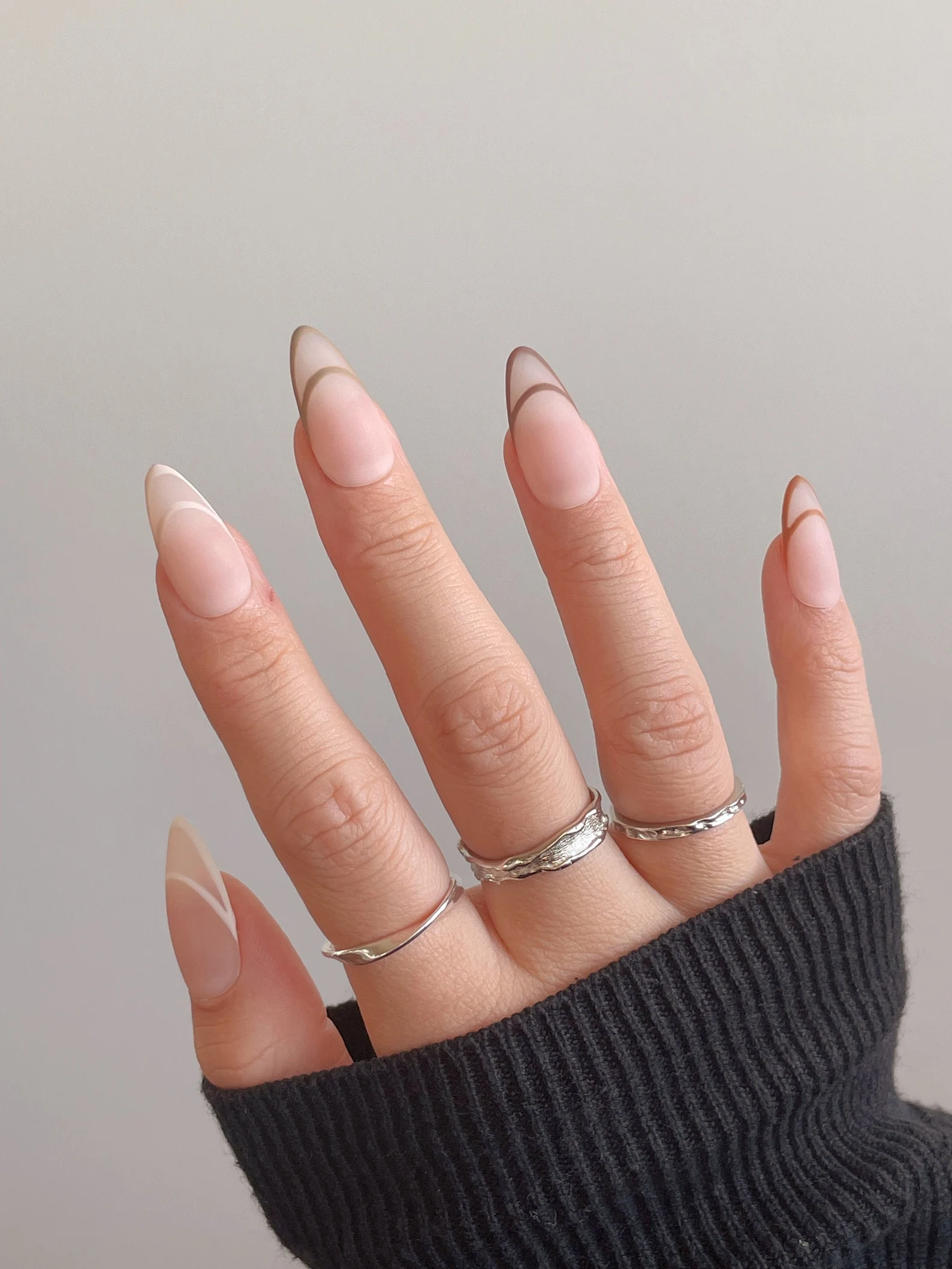 Almond nude nails with thin espresso brown French outline tips