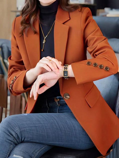 Woman in a rust-colored blazer over a black turtleneck with blue jeans