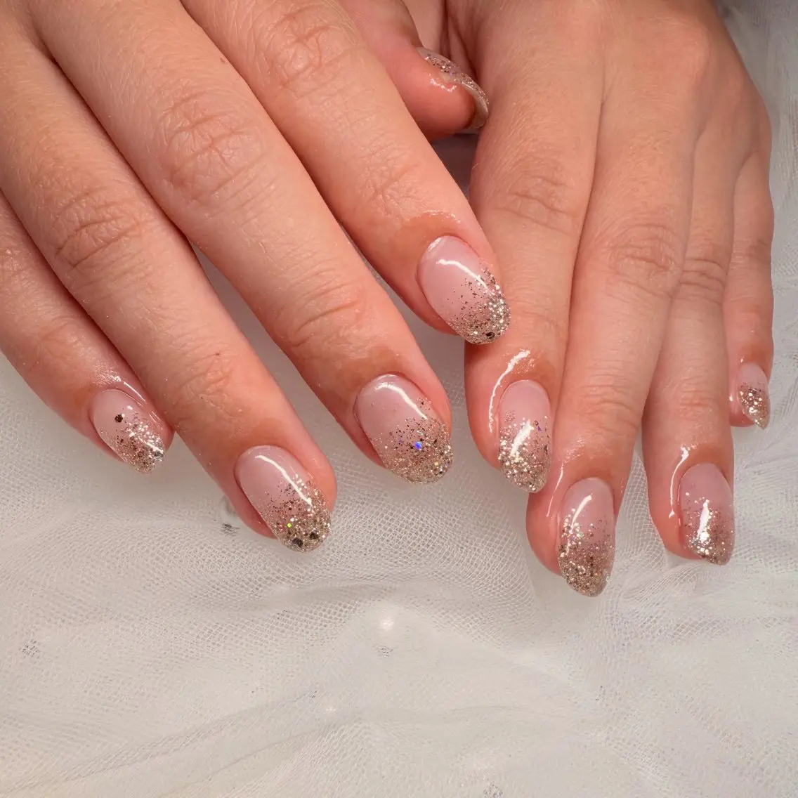 Short almond nude nails with a glitter ombré fade