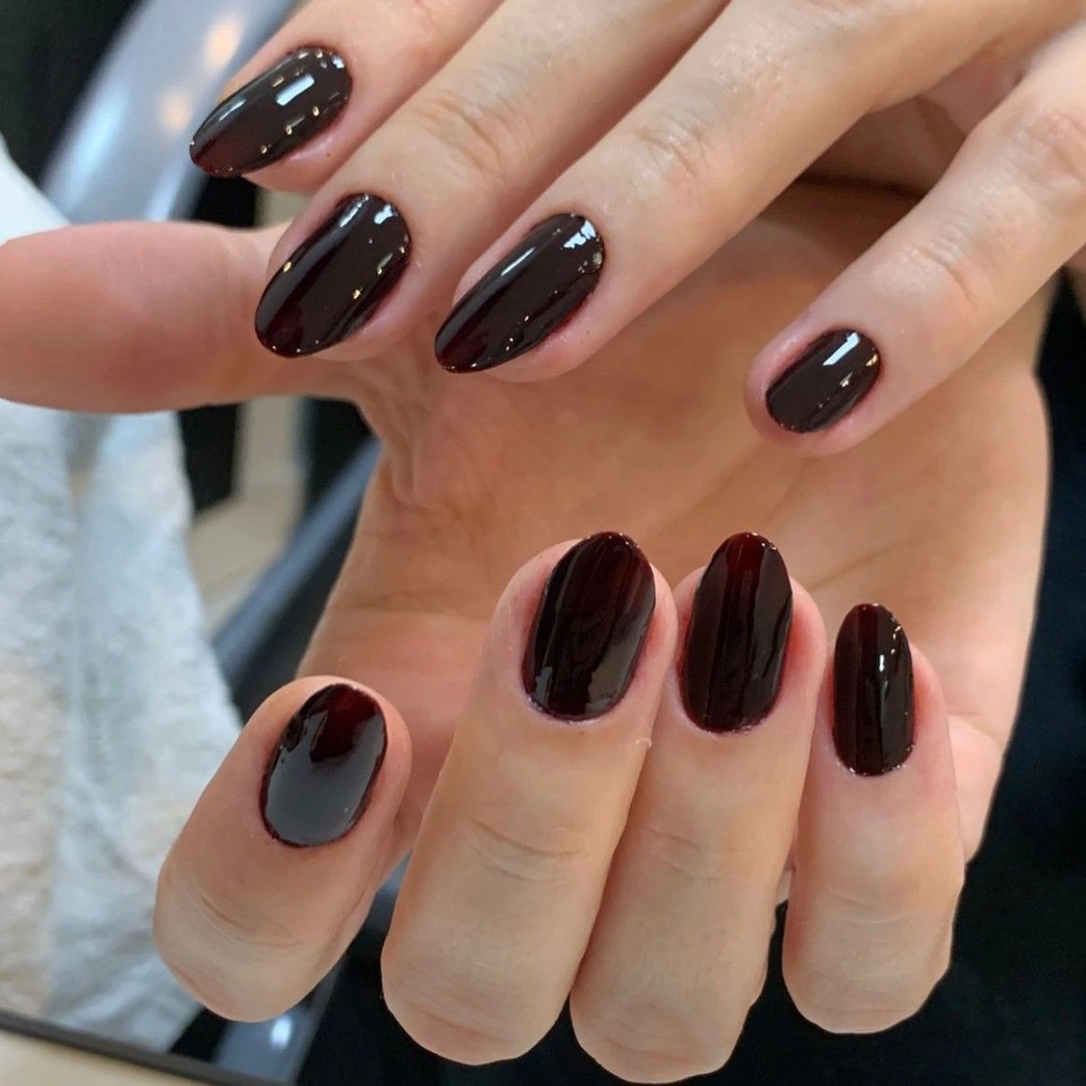 Very dark almost-black cherry polish on short oval nails