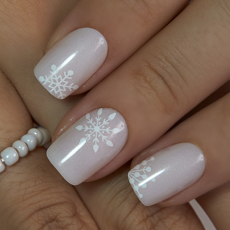 Short oval press-on nails in sheer pink with white snowflake designs