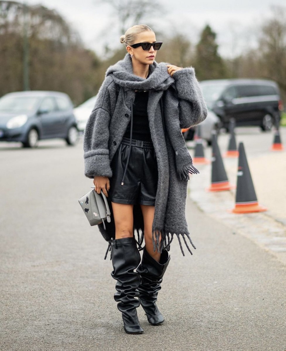 Woman in black slouchy boots, leather shorts and a long fuzzy grey coat