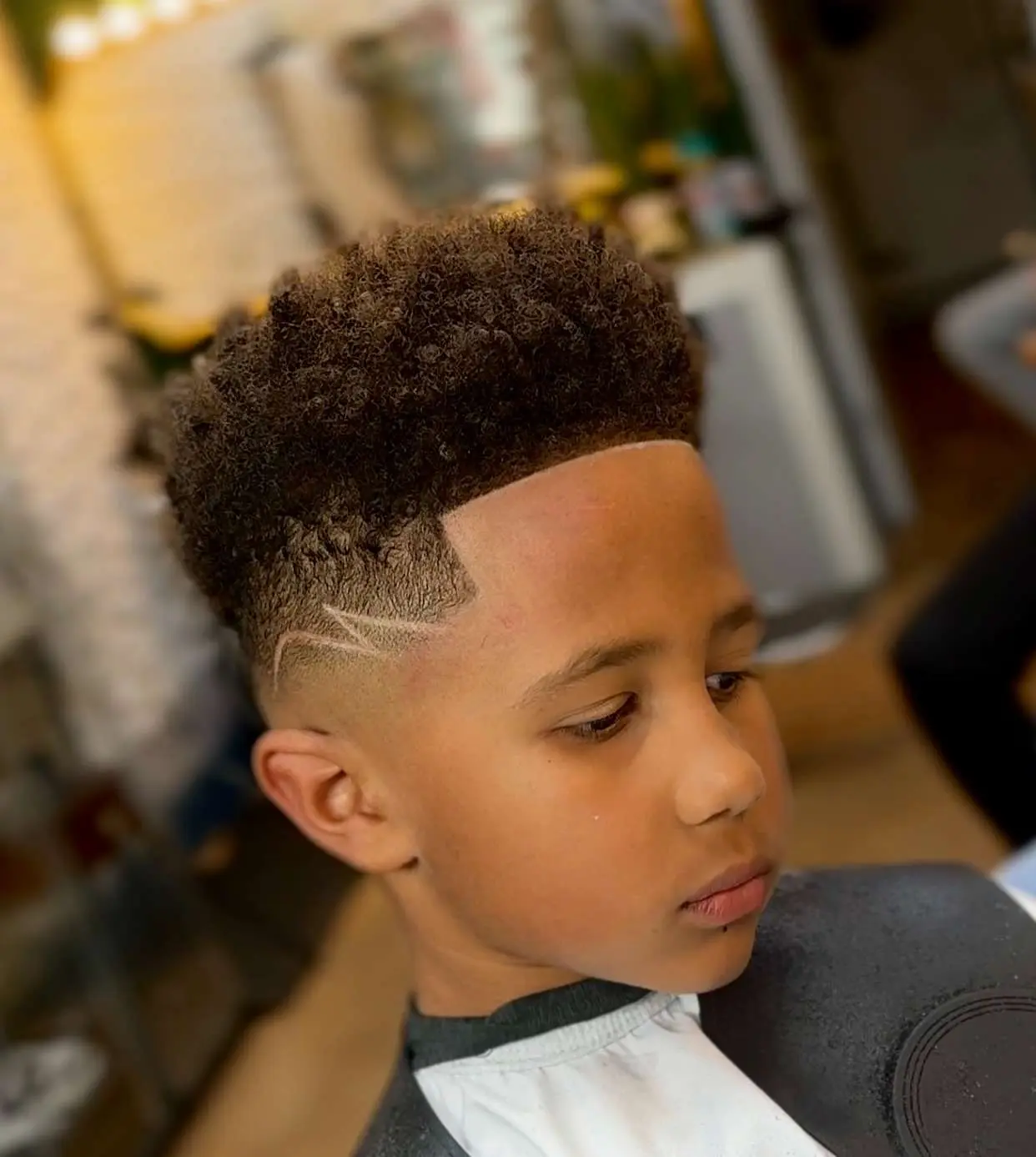 Boy with curly top, tapered sides and a shaved lightning design