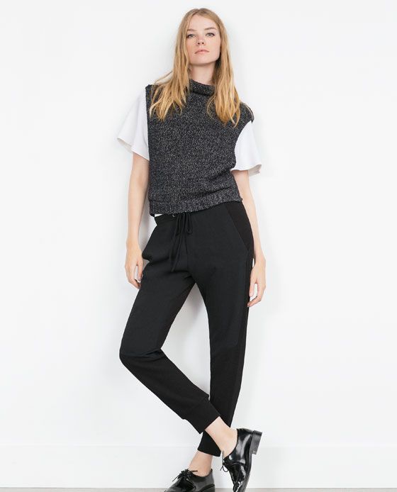 Dark knit sweater vest over white tee with black joggers